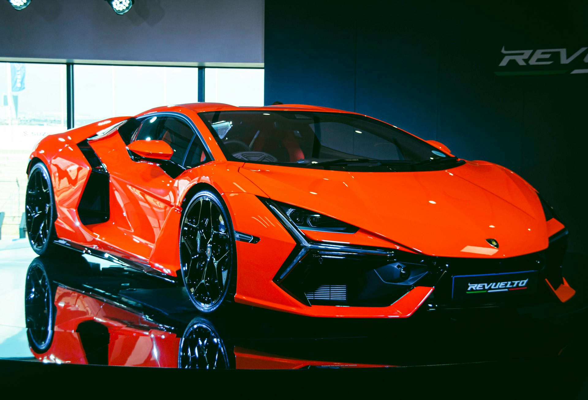 An orange sports car is on display at a show
